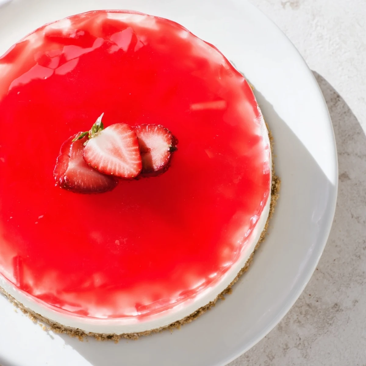 Slice of no bake Greek yogurt jello cheesecake topped with fresh berries on white plate