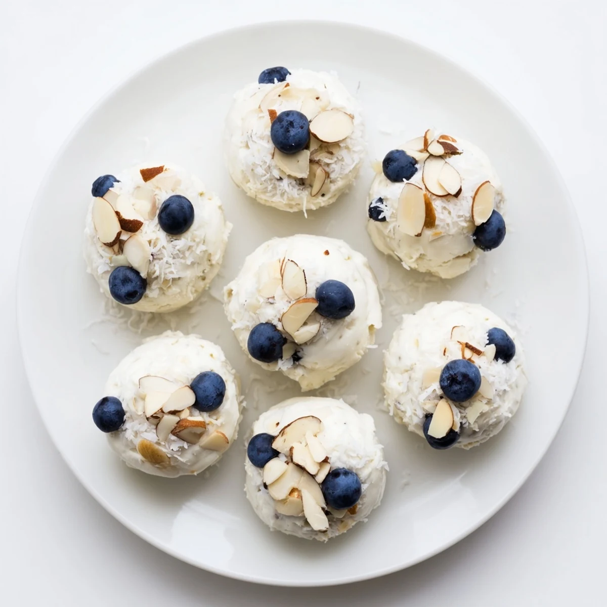 Creamy Greek yogurt bites topped with plump blueberries and optional shredded coconut garnish on baking sheet