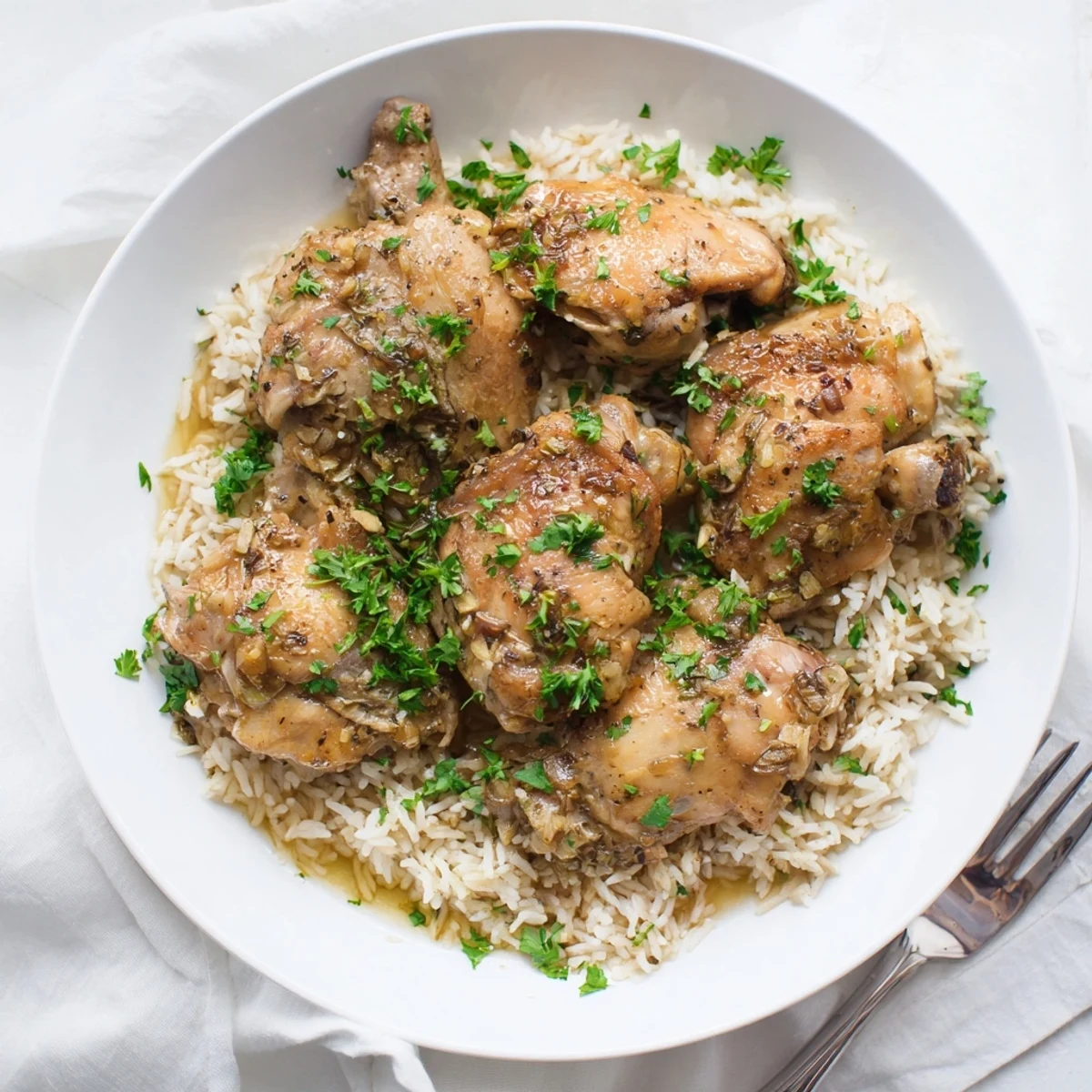 Golden slow cooker lemon herb chicken plated with fluffy white rice and fresh parsley garnish