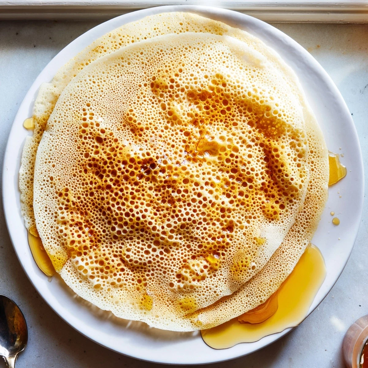 Spongy baghrir with signature honeycomb holes cooked in a skillet for breakfast