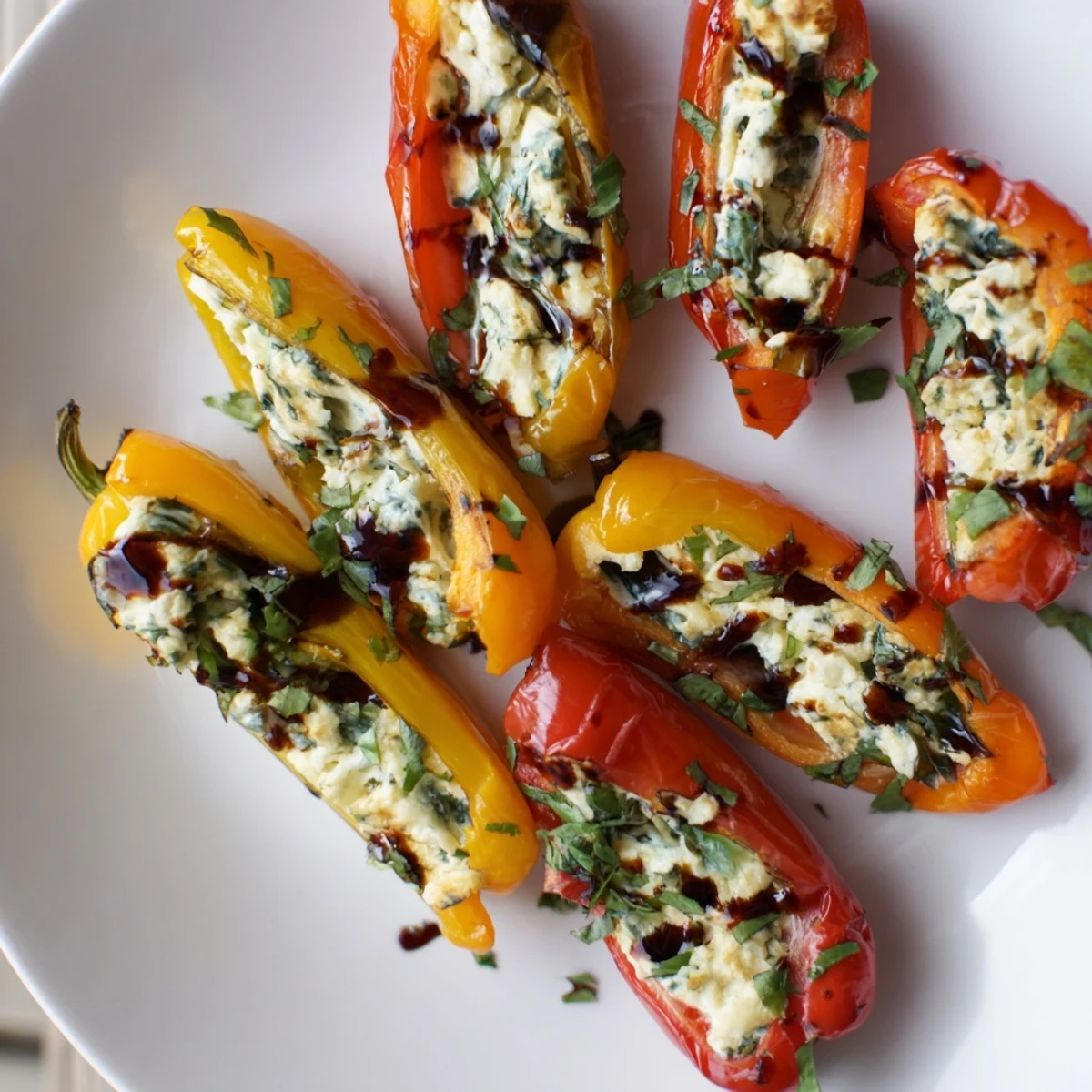 Bite-sized stuffed peppers warm from the oven with melted goat cheese filling and green chive garnish