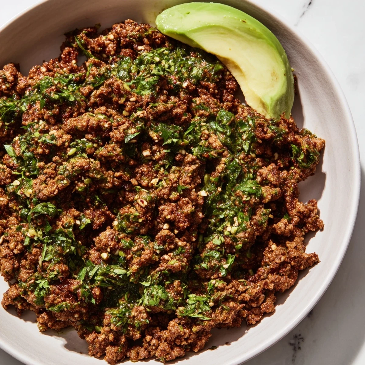 Chimichurri ground beef bowls with bright green herb sauce drizzled over fluffy white rice