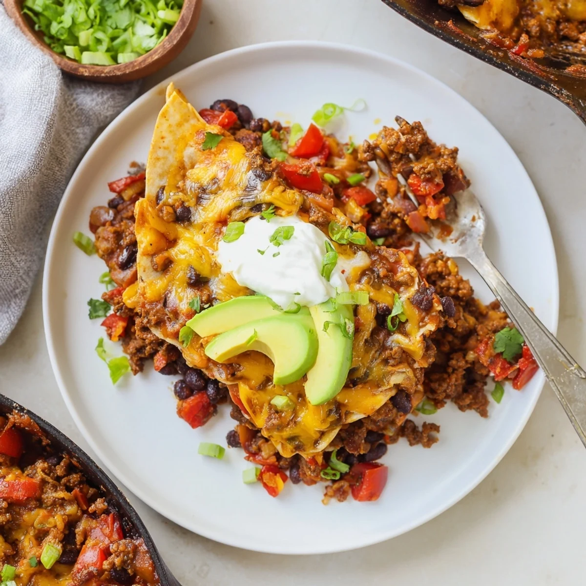 Hearty Beef Skillet Enchiladas topped with diced avocado and sour cream dollop