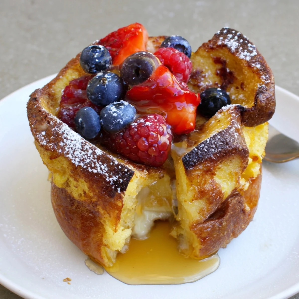 Baked French Toast Cups topped with powdered sugar and warm maple syrup.