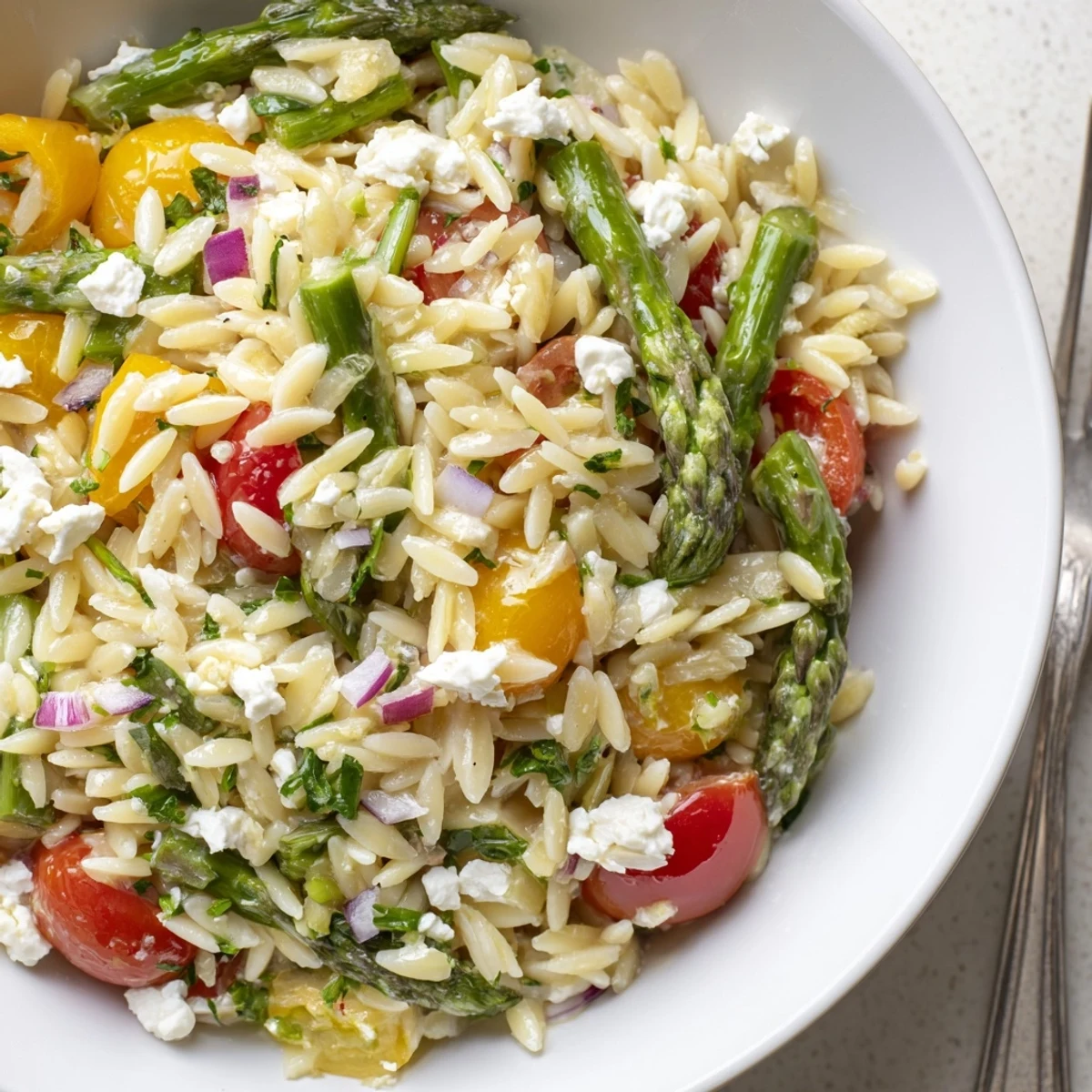 Creamy crumbled feta crowns Asparagus Orzo Salad With Lemon Vinaigrette, chilled for picnics