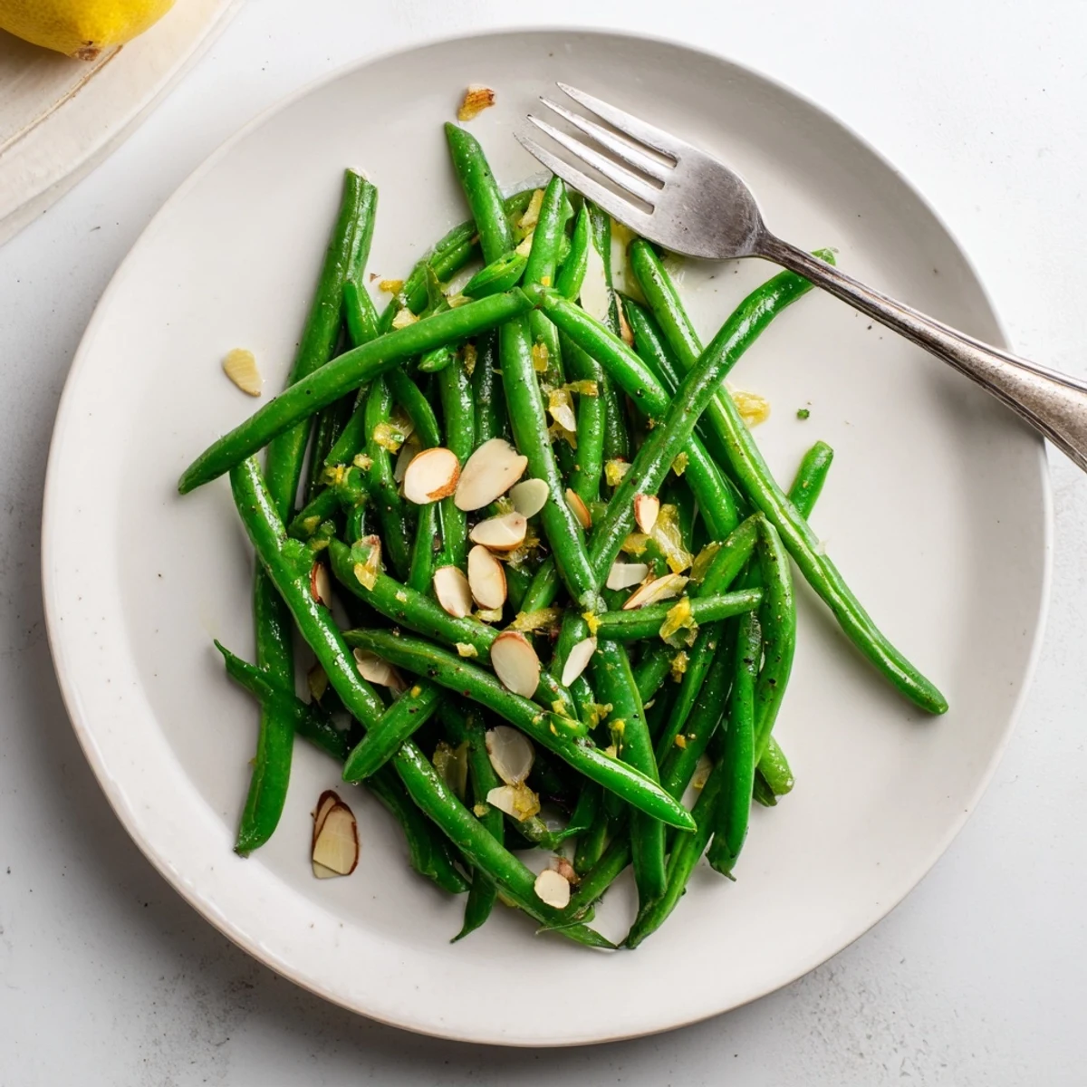 Fresh green beans sautéed with garlic in olive oil, bright and crisp on a white serving plate.