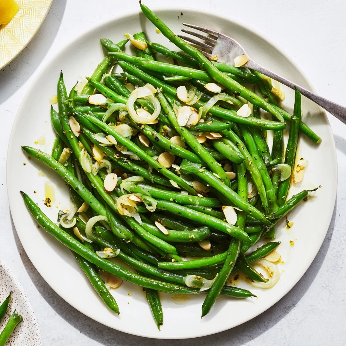 Vibrant sautéed green beans tossed with sliced garlic, drizzled with olive oil and garnished with toasted almonds.