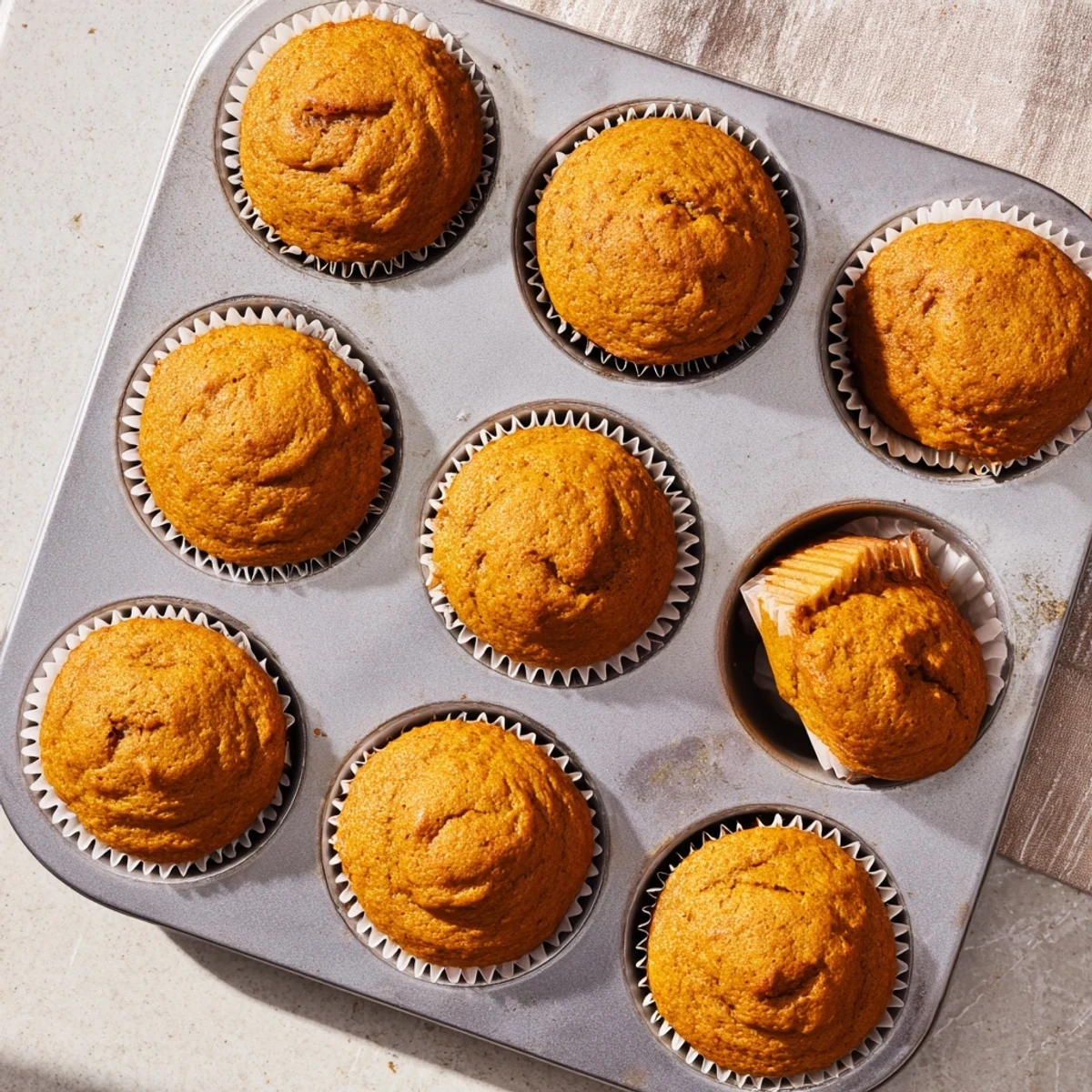 Golden brown pumpkin banana muffins topped with cinnamon sugar and fresh banana slices