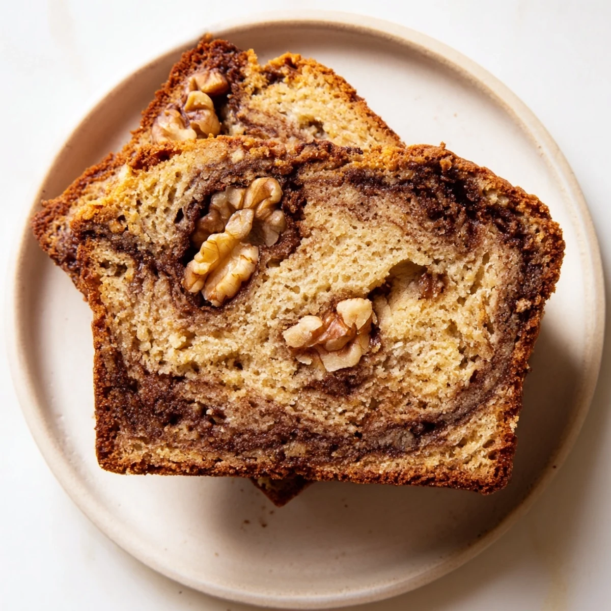 Golden brown banana nut bread loaf with walnuts and cinnamon swirl on wooden board
