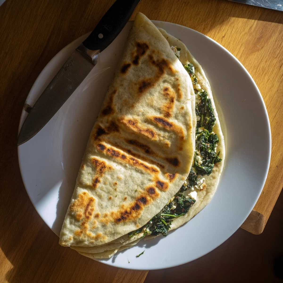 Flaky Turkish Gozleme flatbread layered with melted feta and wilted spinach, sliced into pieces