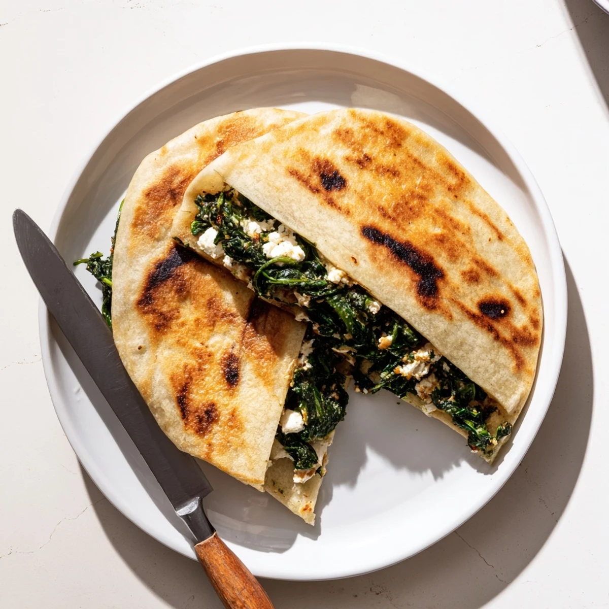 Handheld Turkish Gozleme stuffed with savory spinach and creamy feta cheese, ready to serve