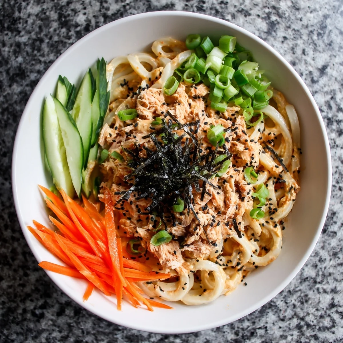 Japanese-style spicy tuna udon served with scallions, pickled ginger, and toasted sesame seed garnish