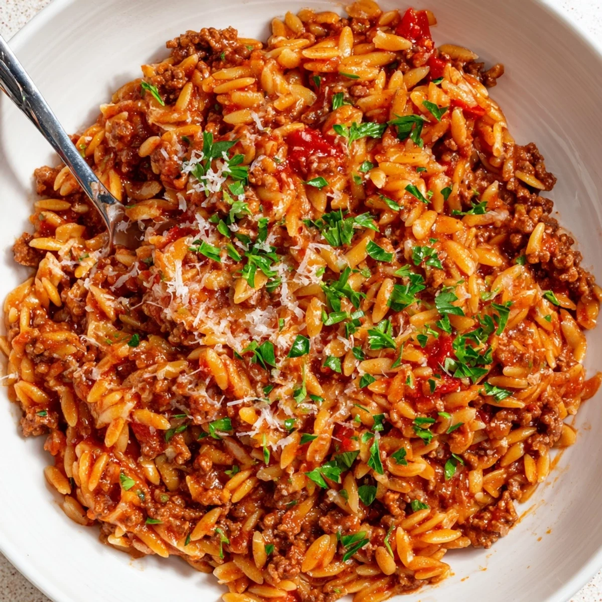Ground Beef Orzo Greek Manestra bubbling in a pot, tomato aroma rising  
