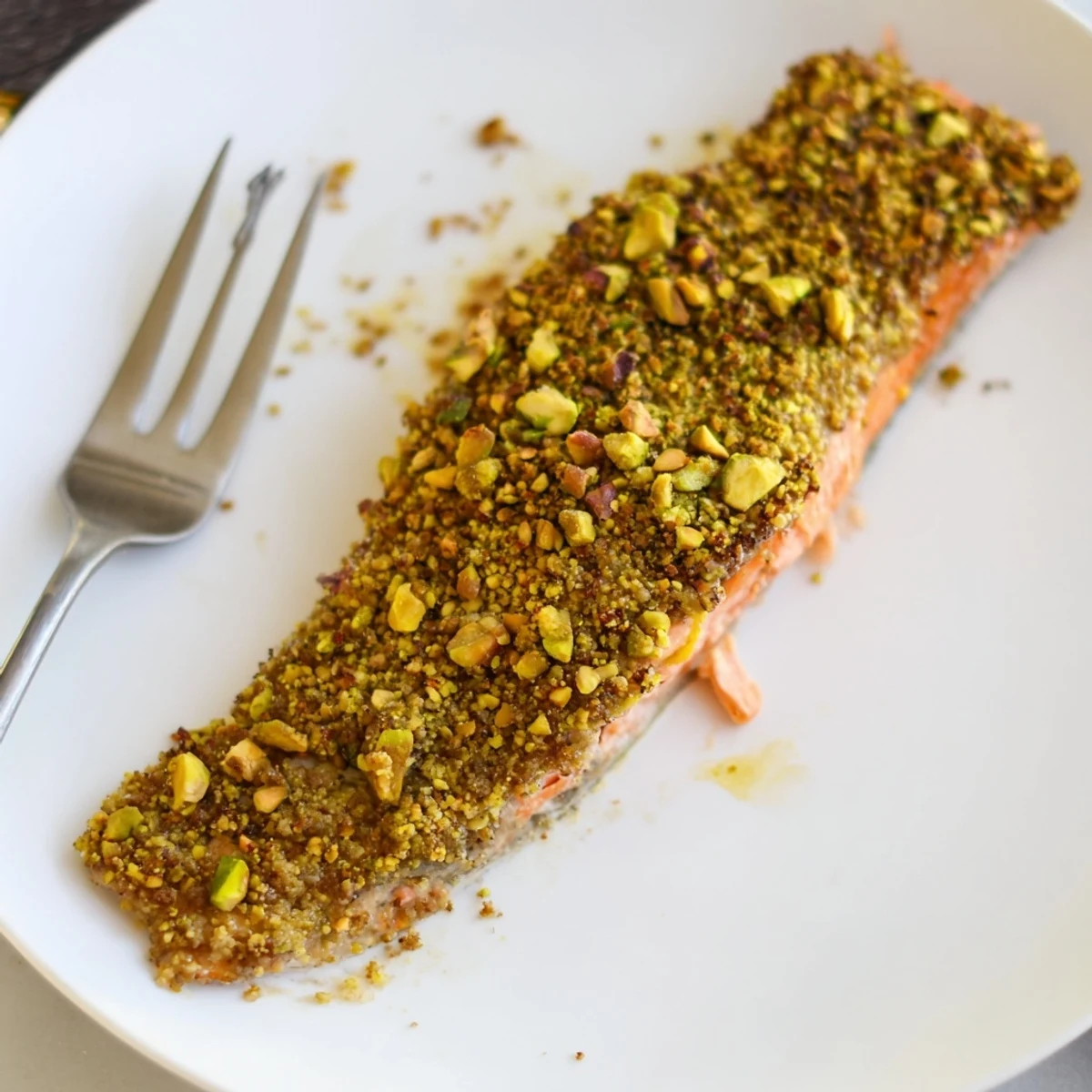 Crispy pistachio-crusted maple salmon fillets served hot on a white dinner plate