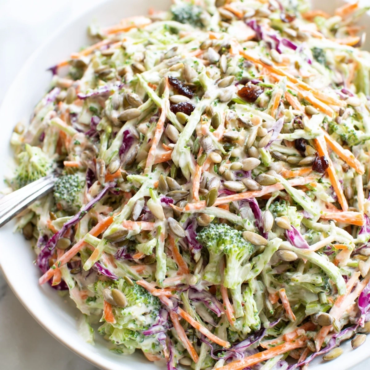 Creamy broccoli slaw with shredded carrots and red cabbage in a tangy dressing